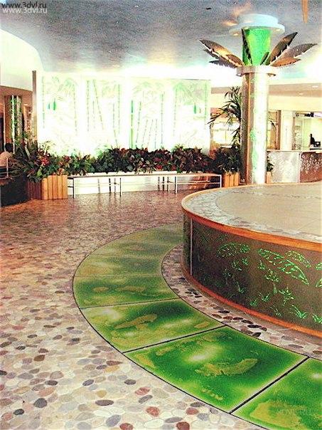 Custom Shaped Green and Yellow Liquid Tiles Upscale Mall in Trinidad Живой пол, волшебство, игра красок и цвета — все эти эпитеты подходят одному материалу, который носит название жидкая плитка. Так что же это за материал? Интерактивный подход к оформлению внутренних помещений все чаще преподносит нам возможность использования новинок в области отделочных материалов, которых с каждым годом появляется все больше и больше.
Производитель 3DVL 
Напольные живые плитки изготавливаются из поликарбоната, но не из простого. Здесь используется фактурный монолитный поликарбонат. Это две поликарбонатные пластины, между которыми залита цветная жидкость. Они соединены между собой посредству технологии сплавления, то есть это монолитное литое изделие, которое гарантировано считается герметичным. Практически все производители дают гарантию в десять лет, за этот срок герметичность изделия не утратит своих показателей.

Какими еще положительными качествами обладает жидкая плитка?

    Высокий показатель устойчивости к истиранию. Плитку часто по данному показателю сравнивают с материалом, которым покрывают сцены театров, залов и так далее.
    Высокая прочность.
    Под данный материал можно установить систему «теплый пол». Единственное условие — температура теплоносителя не должна превышать +30° С.
    Плитка имеет нескользящую поверхность, поэтому ее можно укладывать в такие помещения, как ванная, душевая, бассейны.
    Она не выгорает под действием прямых солнечных лучей, и никогда не выцветает.
    Поликарбонат, из которого изготавливается живой пол, можно чистить и мыть любыми моющими средствами. Он устойчив к любому химическому воздействию.
    Этот материал не горит, что является основным требованием пожарной безопасности.
    С помощью этого отделочного материала можно снизить проникновение шума с нижних этажей, то есть он выполняет функции звукоизоляционного материала.

    Жидкий наполнитель, который заливают между поликарбонатными пластинами, не имеет вредных для человеческого организма веществ, что является немаловажным фактором.

Почему плитку называют «живой пол»? Все дело в том, что внутри этого изделия размещен жидкий наполнитель. При нагружаемости поверхности, к примеру, вы встали на одну из них или поставили стул, происходит сдавливание межпластинчатого пространства. Внутри создается давление. По законам физики жидкость начинает перемещаться в те участки, где давление меньше. Перемещение происходит по компенсационным канавкам.- Custom Shaped Green/Yellow Liquid floor Tiles